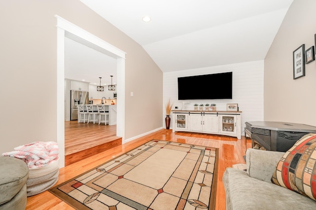 living area with vaulted ceiling and wood finished floors
