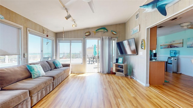 39 Whiting Rd, East Quogue, NY 11942 - living room featuring rail lighting, ceiling fan, light wood-type flooring, vaulted ceiling, and wainscoting