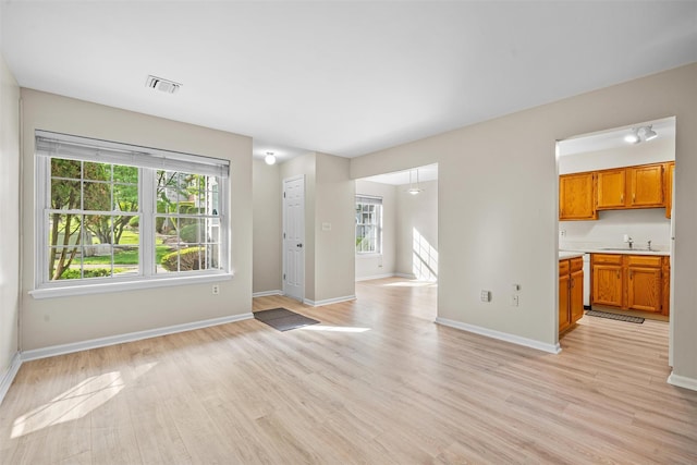 65 Jimal Dr, Middletown, NY 10940 - unfurnished living room featuring healthy amount of natural light, a sink, light wood finished floors, and baseboards