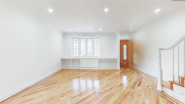 unfurnished living room with stairs, wood finished floors, recessed lighting, baseboards, and crown molding