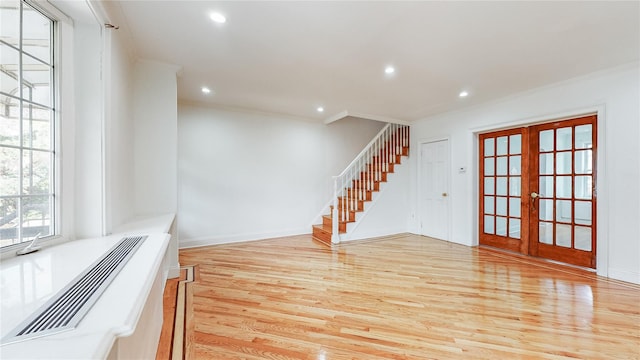 unfurnished living room featuring ornamental molding, french doors, light wood finished floors, stairs, and recessed lighting