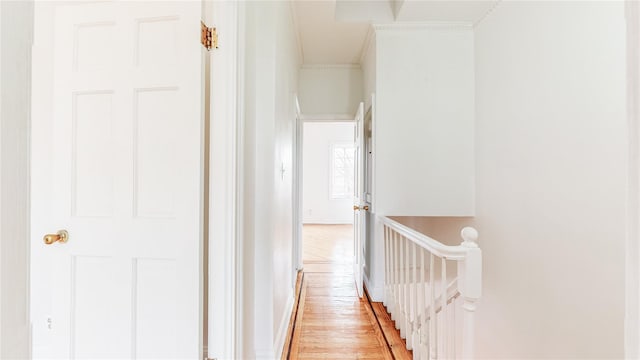 hallway featuring crown molding, light wood-style flooring, baseboards, and an upstairs landing