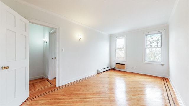 empty room featuring light wood-style flooring, crown molding, baseboard heating, and baseboards