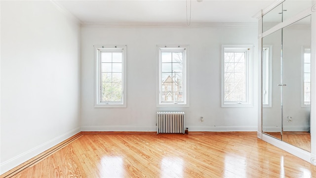 spare room with radiator heating unit, crown molding, wood finished floors, and baseboards