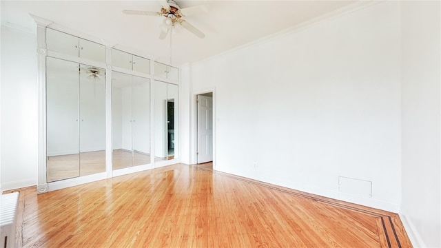 unfurnished bedroom with multiple closets, light wood finished floors, crown molding, baseboards, and a ceiling fan