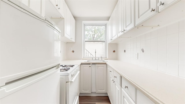 kitchen with white appliances, a sink, white cabinetry, and tasteful backsplash