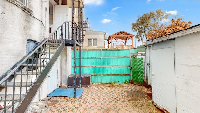 view of patio featuring central AC unit, fence, stairs, and a gazebo
