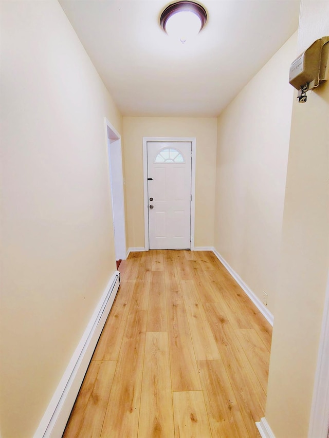 doorway to outside with a baseboard heating unit, light wood finished floors, and baseboards