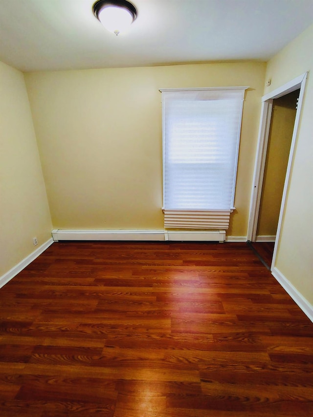 spare room featuring baseboards, wood finished floors, and a baseboard radiator