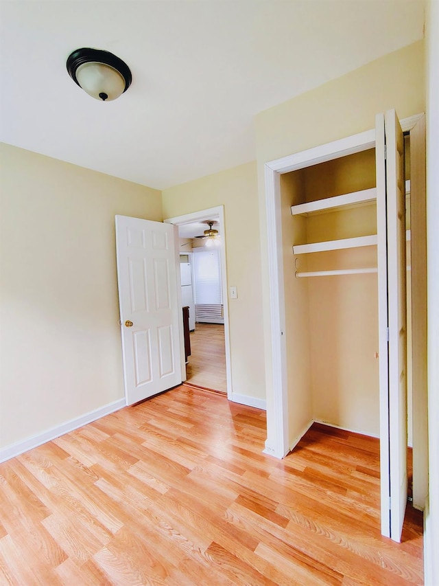unfurnished bedroom featuring a closet, light wood-type flooring, and baseboards
