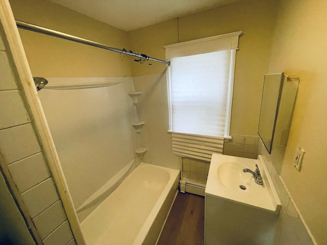 full bathroom featuring baseboard heating, vanity, wood finished floors, and tub / shower combination