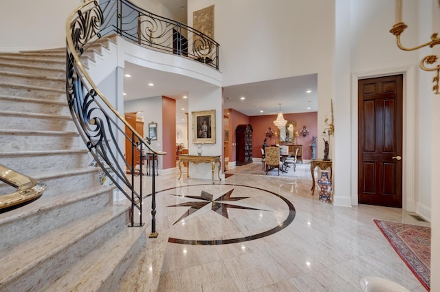 foyer featuring a high ceiling, baseboards, marble tiled floors, and stairway