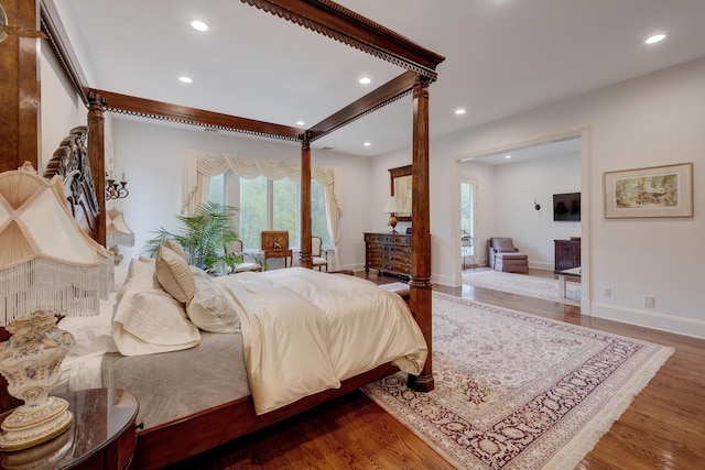 bedroom with multiple windows, recessed lighting, wood finished floors, ornate columns, and baseboards