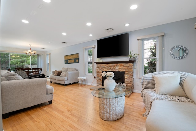 85 Mowbray St, Patchogue, NY 11772 - living area with a chandelier, light wood-type flooring, a stone fireplace, and recessed lighting