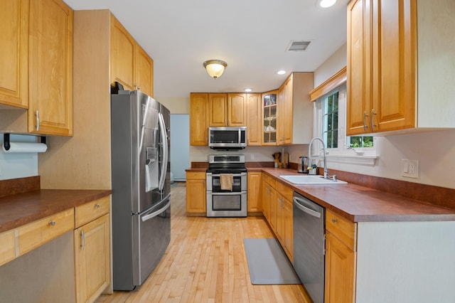 85 Mowbray St, Patchogue, NY 11772 - kitchen featuring stainless steel appliances, dark countertops, light wood-style floors, glass insert cabinets, and recessed lighting
