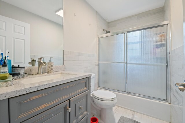 85 Mowbray St, Patchogue, NY 11772 - full bathroom featuring vanity, combined bath / shower with glass door, and tile walls