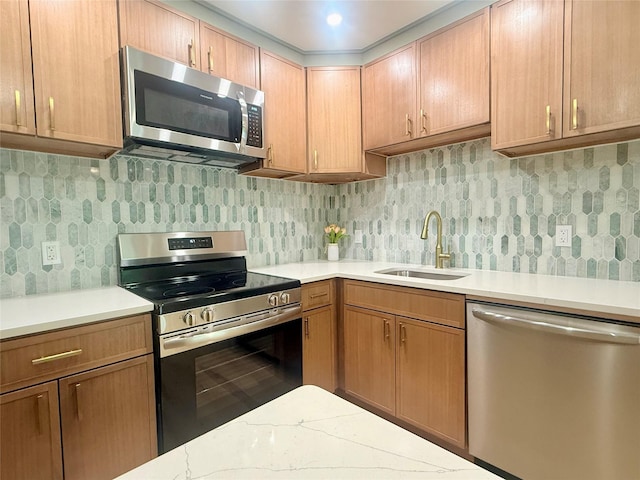 kitchen with appliances with stainless steel finishes, a sink, decorative backsplash, and brown cabinetry