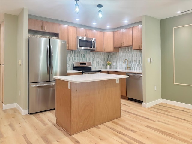 kitchen with appliances with stainless steel finishes, light wood-style floors, light countertops, a center island, and baseboards