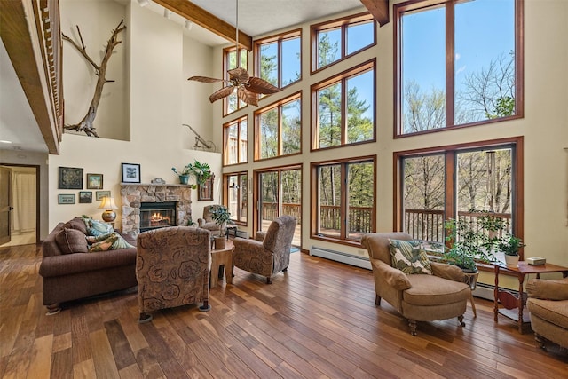 216 Cortese Rd, Call Listing Agent, PA 18405 - living room featuring a baseboard radiator, a towering ceiling, a stone fireplace, hardwood / wood-style flooring, and beamed ceiling