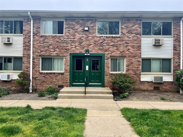 view of property featuring a wall mounted air conditioner and brick siding