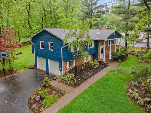view of front of house featuring asphalt driveway, a front yard, an attached garage, a chimney, and brick siding