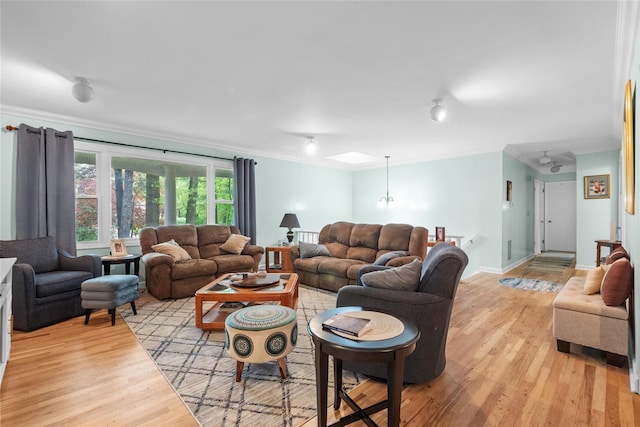 living area with crown molding, light wood-style flooring, and baseboards