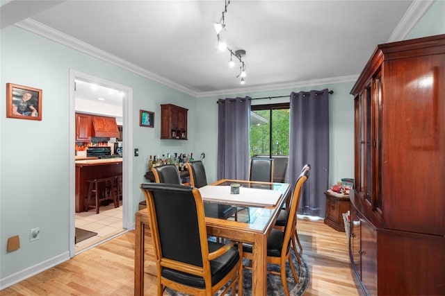 dining area featuring light wood finished floors, ornamental molding, and baseboards