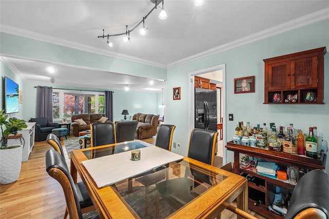 dining area featuring light wood-style flooring and crown molding