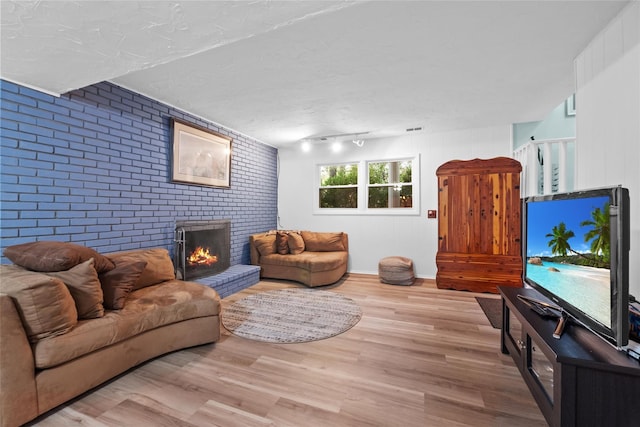 living room featuring brick wall, a fireplace, and wood finished floors
