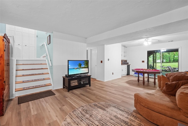 living room with light wood-style flooring, stairs, and a ceiling fan
