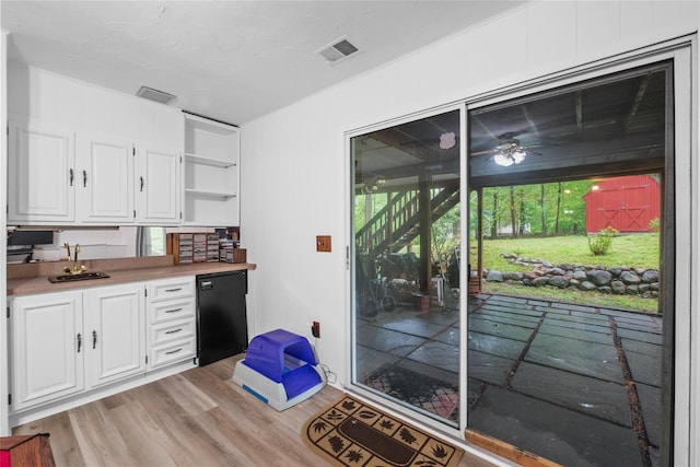 kitchen featuring open shelves, a sink, white cabinetry, light wood-style floors, and light countertops