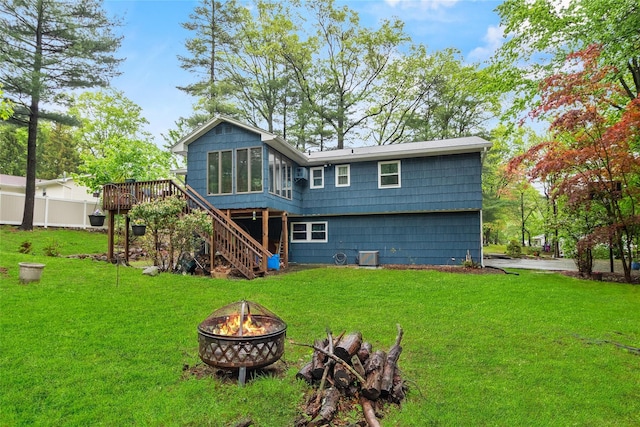 back of property featuring a fire pit, stairs, a deck, and a yard