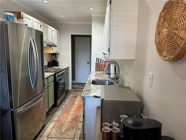 kitchen with freestanding refrigerator, gas range oven, a sink, under cabinet range hood, and ornamental molding