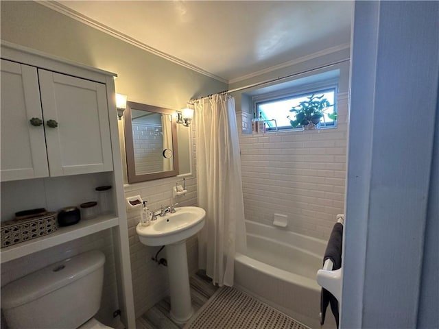 bathroom featuring toilet, shower / bath combination with curtain, crown molding, tile walls, and a sink