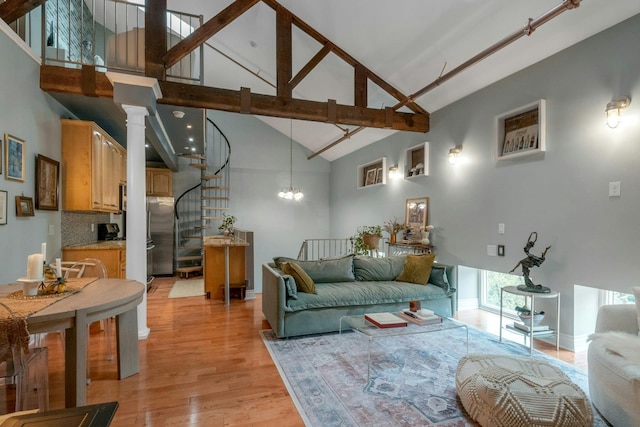 living area featuring high vaulted ceiling, stairway, light wood-style flooring, and a chandelier