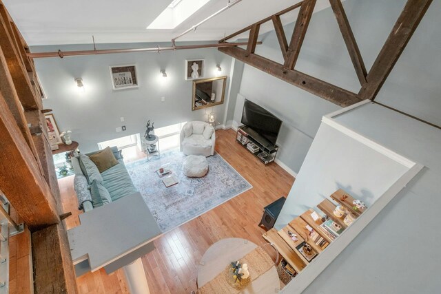 living room with wood finished floors, a skylight, and baseboards