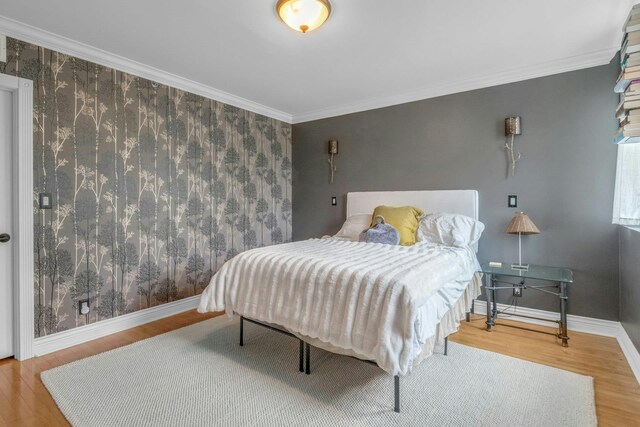 bedroom with wood finished floors, baseboards, and crown molding