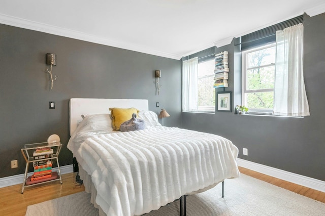 bedroom featuring wood finished floors, ornamental molding, and baseboards