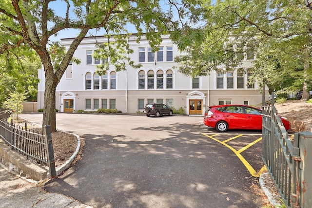 view of property with uncovered parking and fence