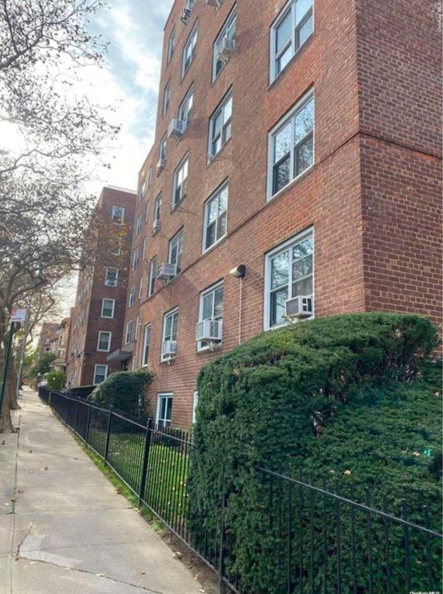 view of apartment building / complex featuring fence and cooling unit