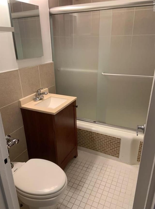 full bathroom featuring an enclosed shower, tile walls, vanity, toilet, and tile patterned flooring