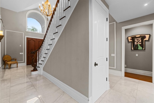 stairs with marble look tile flooring, baseboards, and a chandelier