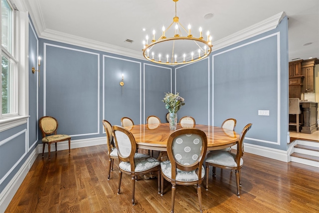 dining area with a chandelier, a decorative wall, crown molding, wood finished floors, and baseboards