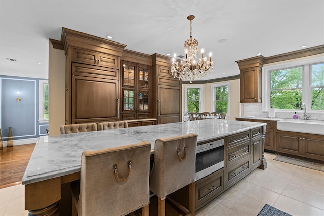 kitchen with a sink, a chandelier, a breakfast bar area, light tile patterned floors, and recessed lighting