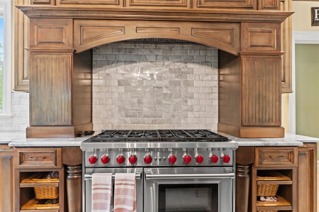 kitchen with double oven range, decorative backsplash, light countertops, and brown cabinetry