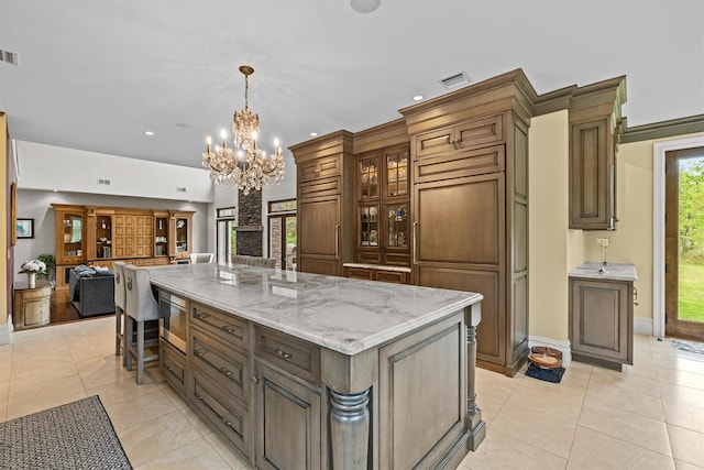 kitchen with a chandelier, open floor plan, stainless steel microwave, hanging light fixtures, and a breakfast bar