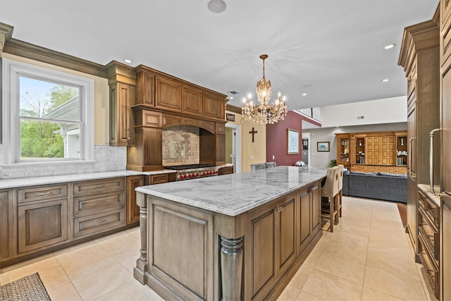 kitchen featuring open floor plan, backsplash, a large island, light stone counters, and a chandelier