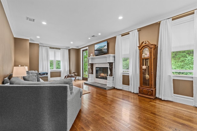 living room featuring ornamental molding, a premium fireplace, wood finished floors, baseboards, and recessed lighting