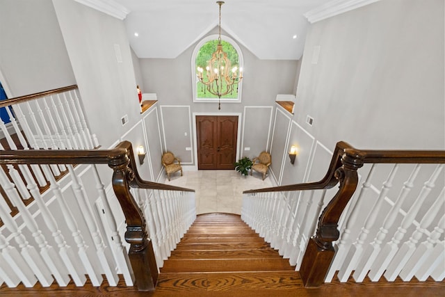 stairs featuring a chandelier, a decorative wall, and lofted ceiling