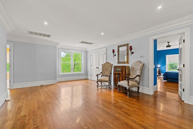 sitting room featuring plenty of natural light, wood finished floors, crown molding, baseboards, and recessed lighting